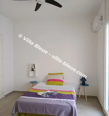 Suite with colorful linens bed and ceiling fan